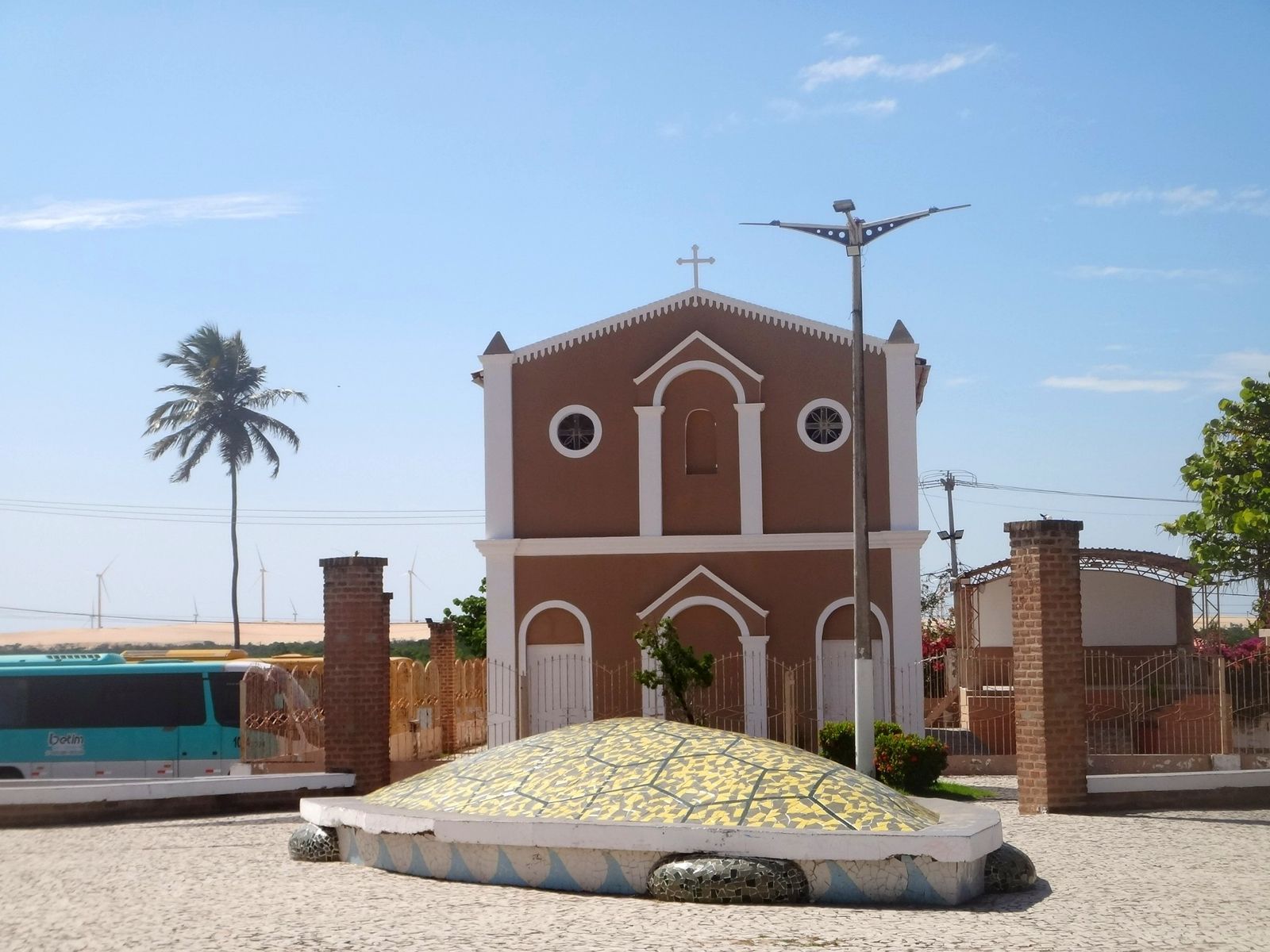 Igreja histórica de fachada marrom e detalhes brancos, vista da praça de Fortim