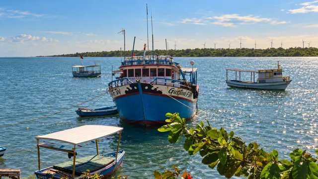 Barcos atracados no rio, com eólicas ao fundo