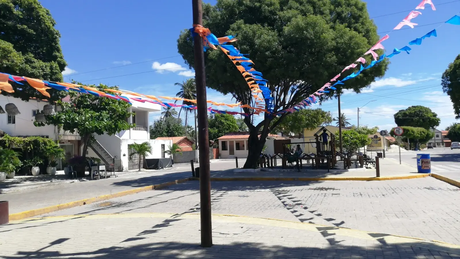 Praça arborizada com bandeirolas coloridas em Pontal