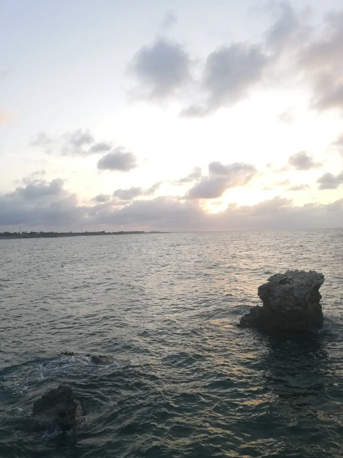 Pedra isolada no mar sob céu de fim de tarde