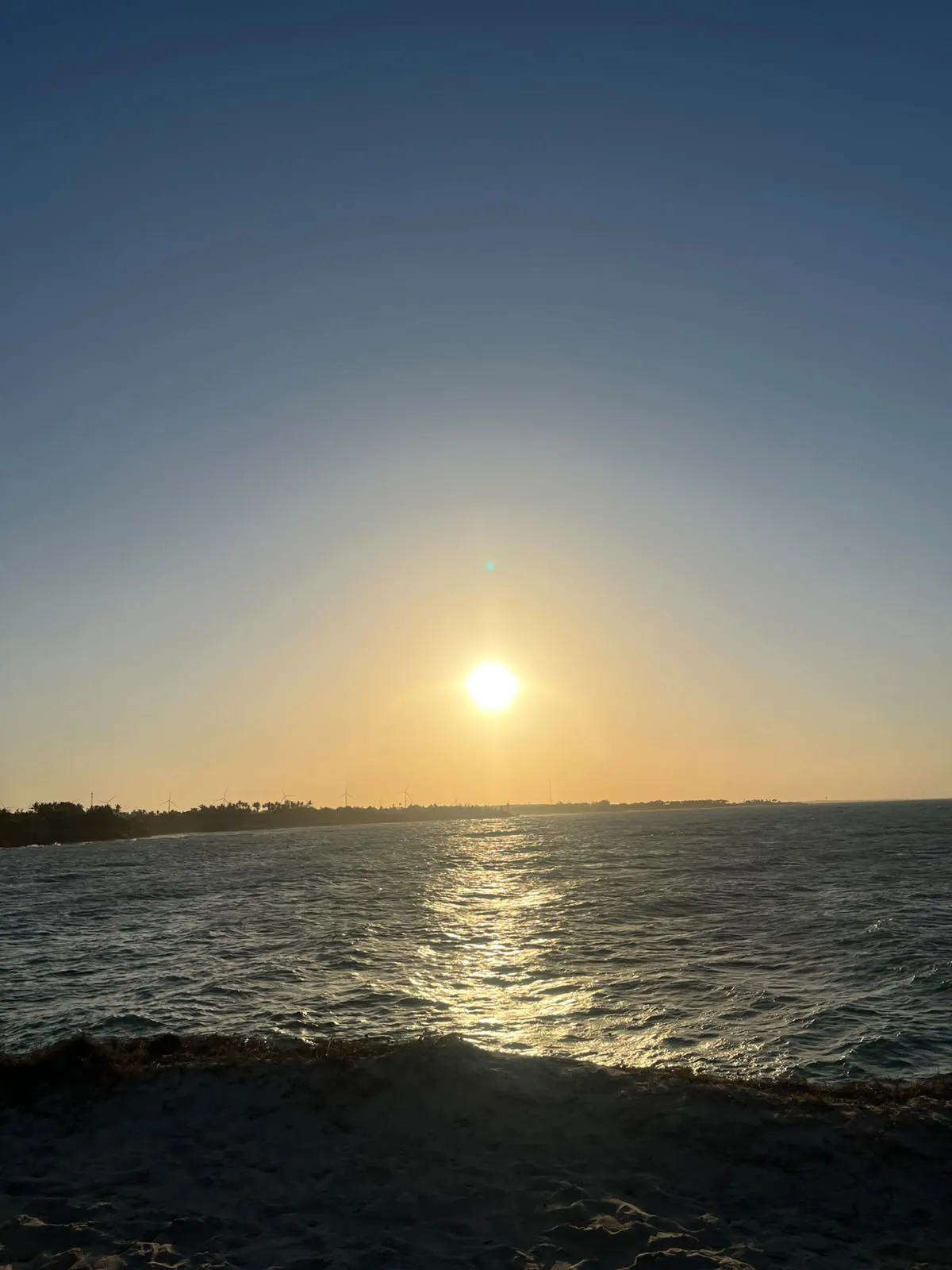 Sol baixo sobre o mar, visto do alto da falésia